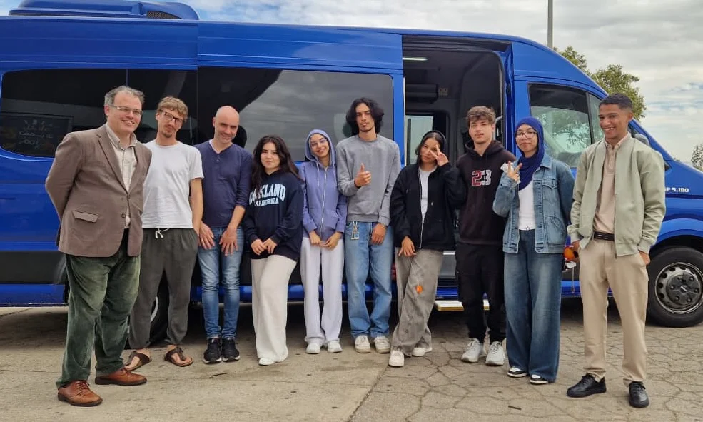 A group posing together beside a blue minibus