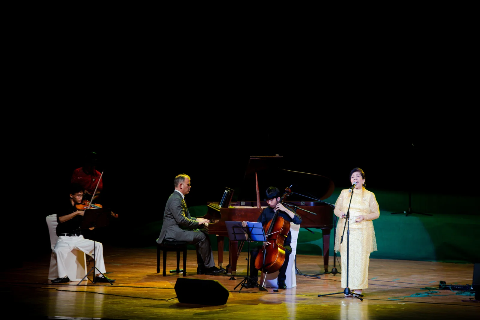 A vocalist performing with piano, violin, and cello at the National Theatre