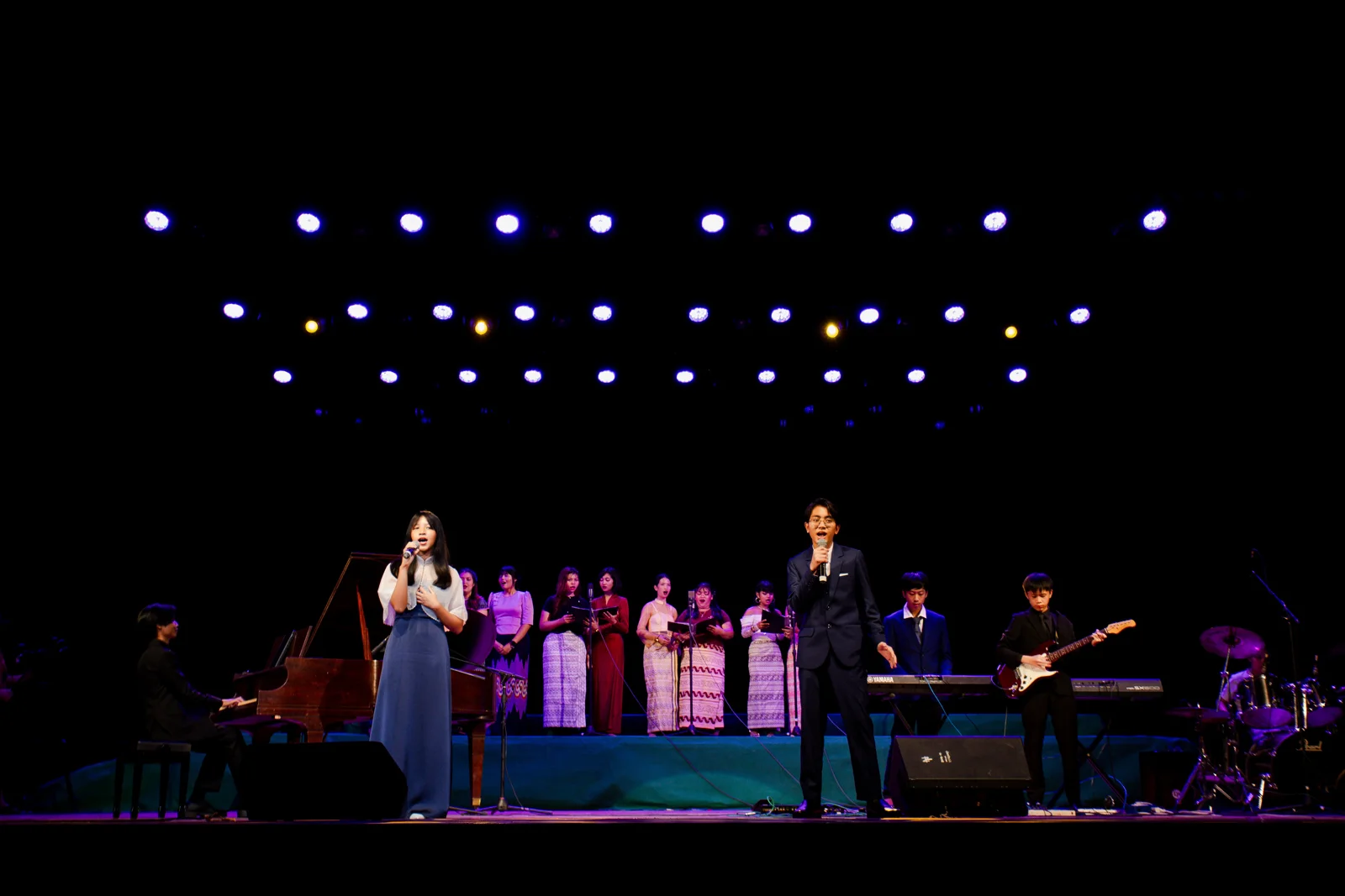 Vocalists, instrumentalists, and choir members performing together at the National Theatre
