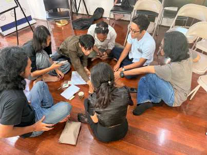 Participants working together around notebooks during a creativity workshop in Mandalay